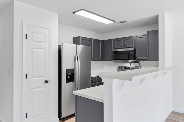222 Swaying Pine Ct, Crestview, FL 32539 - kitchen with stainless steel appliances, a breakfast bar, a peninsula, light countertops, and tasteful backsplash