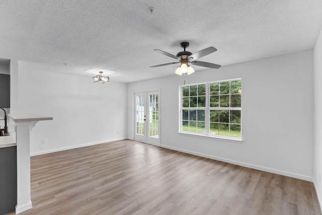 222 Swaying Pine Ct, Crestview, FL 32539 - unfurnished living room featuring light wood-type flooring, a textured ceiling, a ceiling fan, french doors, and a chandelier