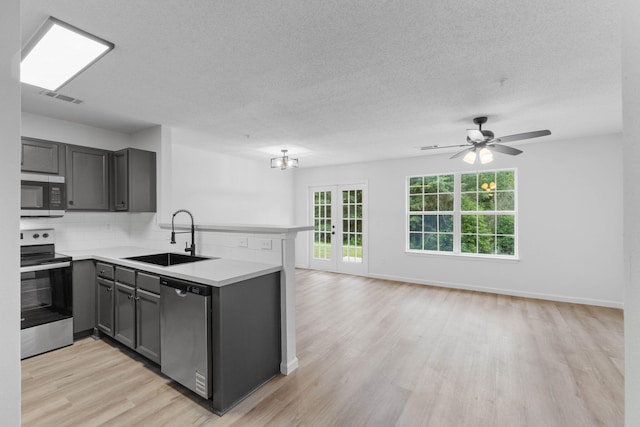 222 Swaying Pine Ct, Crestview, FL 32539 - kitchen with appliances with stainless steel finishes, a peninsula, light wood-style flooring, gray cabinetry, and decorative backsplash
