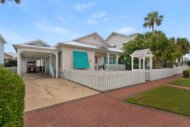 4460 Ocean View Dr, Destin, FL 32541 - view of front of house with driveway, covered porch, a fenced front yard, a metal roof, and a carport