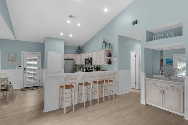4460 Ocean View Dr, Destin, FL 32541 - kitchen with stainless steel appliances, wainscoting, high vaulted ceiling, open shelves, and a breakfast bar area