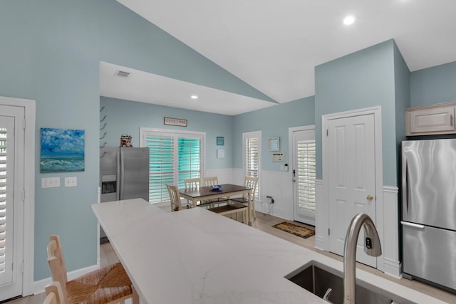 4460 Ocean View Dr, Destin, FL 32541 - kitchen with freestanding refrigerator, light stone counters, a wainscoted wall, recessed lighting, and high vaulted ceiling