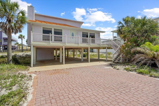8147 White Sands Blvd, Navarre, FL 32566 - view of front of house featuring a carport, decorative driveway, stairs, and a chimney