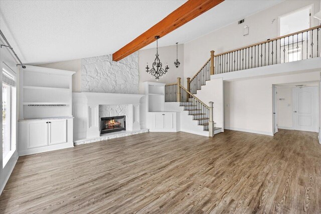 8147 White Sands Blvd, Navarre, FL 32566 - unfurnished living room featuring high vaulted ceiling, wood finished floors, stairway, beamed ceiling, and a fireplace