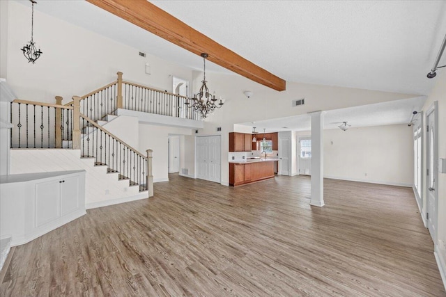 8147 White Sands Blvd, Navarre, FL 32566 - unfurnished living room featuring a chandelier, wood finished floors, beam ceiling, high vaulted ceiling, and stairs