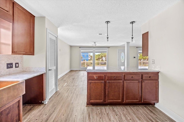 8147 White Sands Blvd, Navarre, FL 32566 - kitchen featuring light wood finished floors, backsplash, light countertops, a textured ceiling, and decorative light fixtures