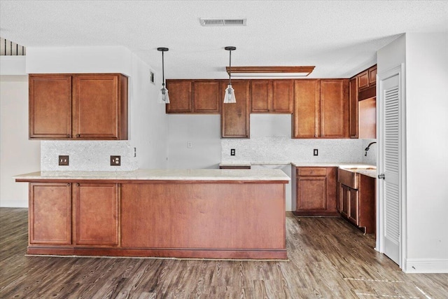 8147 White Sands Blvd, Navarre, FL 32566 - kitchen featuring dark wood-style flooring, decorative backsplash, brown cabinets, hanging light fixtures, and a textured ceiling