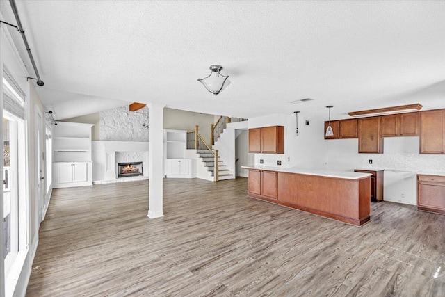 8147 White Sands Blvd, Navarre, FL 32566 - kitchen featuring wood finished floors, brown cabinetry, a textured ceiling, a large fireplace, and open floor plan