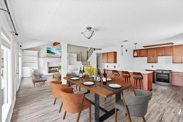 8147 White Sands Blvd, Navarre, FL 32566 - dining area with a fireplace, light wood finished floors, a textured ceiling, stairway, and lofted ceiling