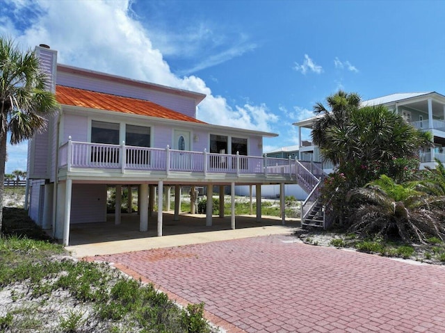 8147 White Sands Blvd, Navarre, FL 32566 - rear view of house featuring a carport, decorative driveway, a metal roof, stairs, and a chimney