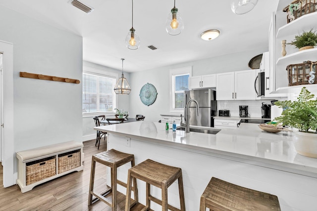 198 Somerset Bridge Rd Unit 143, Santa Rosa Beach, FL 32459 - kitchen with a peninsula, white cabinetry, light wood finished floors, appliances with stainless steel finishes, and open shelves