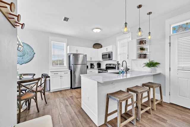 198 Somerset Bridge Rd Unit 143, Santa Rosa Beach, FL 32459 - kitchen with appliances with stainless steel finishes, light wood-type flooring, a breakfast bar, a peninsula, and white cabinetry