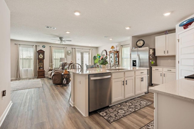 4649 Naval Ct, Crestview, FL 32539 - kitchen featuring stainless steel appliances, a textured ceiling, wood finished floors, ceiling fan, and white cabinetry