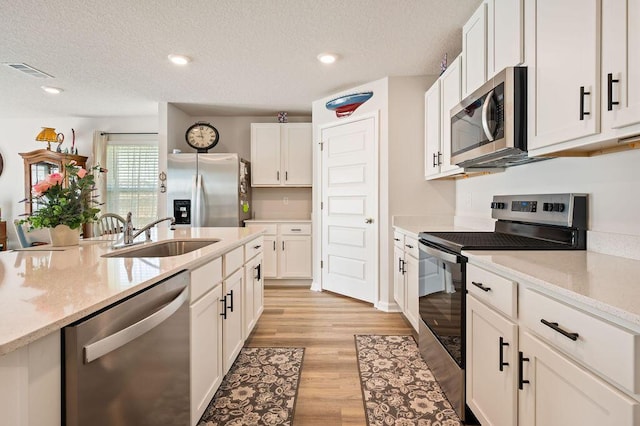 4649 Naval Ct, Crestview, FL 32539 - kitchen featuring stainless steel appliances, white cabinets, light wood finished floors, a textured ceiling, and light stone counters
