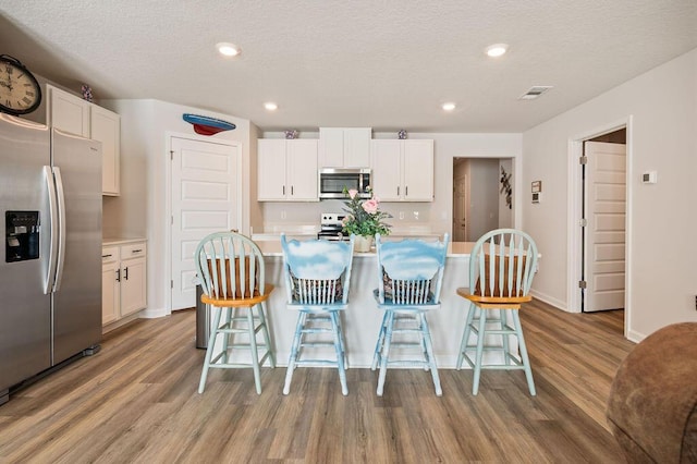4649 Naval Ct, Crestview, FL 32539 - kitchen with stainless steel appliances, wood finished floors, white cabinetry, a textured ceiling, and recessed lighting