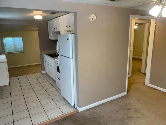 947 Don Dr, Fort Walton Beach, FL 32547 - kitchen with freestanding refrigerator, white cabinetry, ceiling fan, and light colored carpet