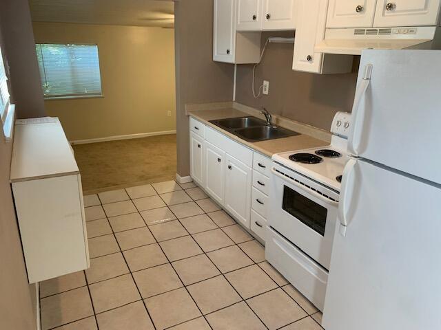947 Don Dr, Fort Walton Beach, FL 32547 - kitchen with white appliances, under cabinet range hood, light tile patterned floors, white cabinets, and light countertops