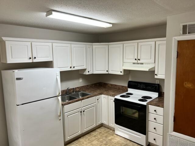 947 Don Dr, Fort Walton Beach, FL 32547 - kitchen featuring white appliances, under cabinet range hood, white cabinets, dark countertops, and a textured ceiling