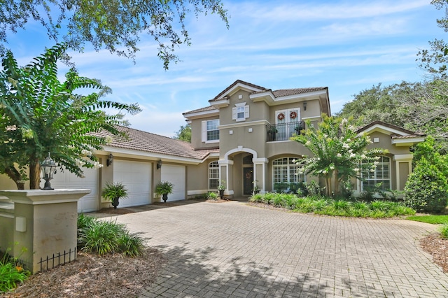 6341 Augusta Cv, Destin, FL 32541 - mediterranean / spanish-style home with a balcony, a tile roof, stucco siding, a garage, and decorative driveway