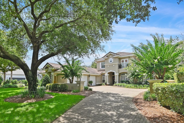 6341 Augusta Cv, Destin, FL 32541 - mediterranean / spanish-style home featuring an attached garage, stucco siding, decorative driveway, a tile roof, and a front lawn