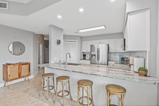 164 Blue Lupine Way Unit 411, Santa Rosa Beach, FL 32459 - kitchen with stainless steel appliances, a peninsula, light stone counters, white cabinets, and tasteful backsplash