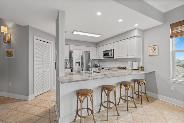 164 Blue Lupine Way Unit 411, Santa Rosa Beach, FL 32459 - kitchen with stainless steel appliances, a peninsula, light stone countertops, white cabinetry, and recessed lighting