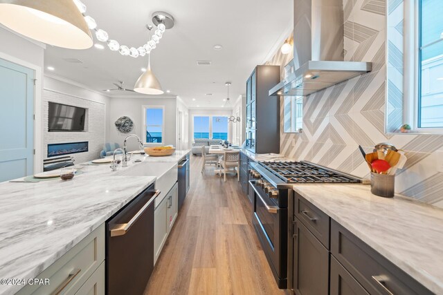 19989 Front Beach Rd, Panama City Beach, FL 32413 - kitchen with appliances with stainless steel finishes, wall chimney exhaust hood, open floor plan, ornamental molding, and light wood-type flooring