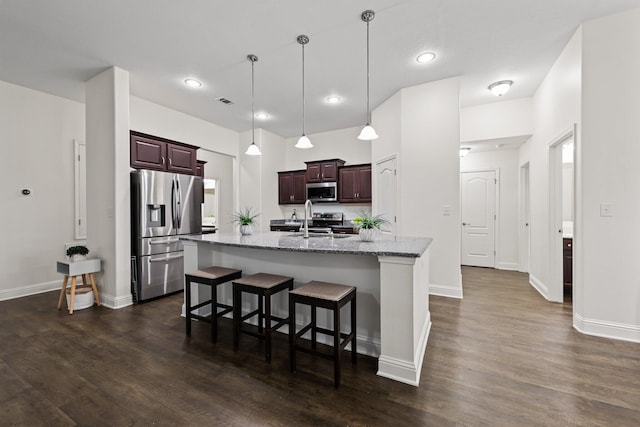 8152 Nevada St, Navarre, FL 32566 - kitchen featuring stainless steel appliances, an island with sink, a breakfast bar, dark wood-style flooring, and light stone countertops