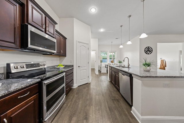 8152 Nevada St, Navarre, FL 32566 - kitchen featuring appliances with stainless steel finishes, dark wood-style floors, light stone countertops, a center island with sink, and decorative light fixtures