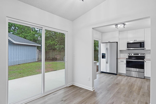 1816 Madelons Path, Fort Walton Beach, FL 32547 - kitchen featuring appliances with stainless steel finishes, light wood-type flooring, white cabinets, decorative backsplash, and lofted ceiling