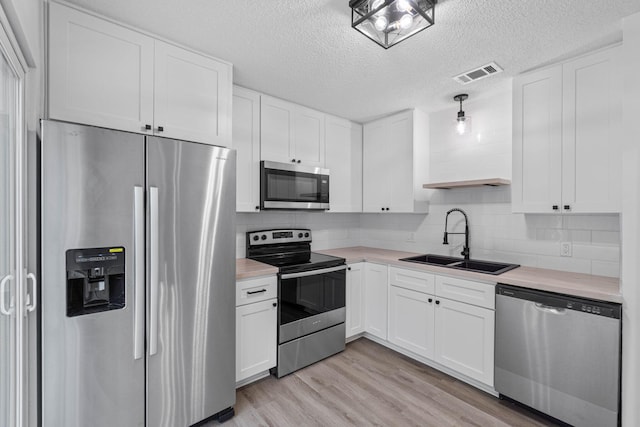1816 Madelons Path, Fort Walton Beach, FL 32547 - kitchen with appliances with stainless steel finishes, light countertops, light wood-style floors, white cabinetry, and a textured ceiling