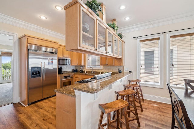 19108 Front Beach Rd Unit A & B, Panama City Beach, FL 32413 - kitchen with appliances with stainless steel finishes, crown molding, a peninsula, light wood-type flooring, and light brown cabinetry