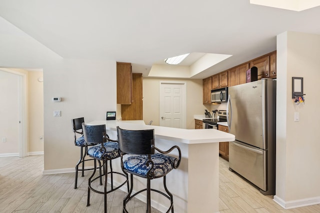 15100 Emerald Coast Pkwy Unit 602, Destin, FL 32541 - kitchen with appliances with stainless steel finishes, light wood-type flooring, brown cabinets, a breakfast bar area, and light countertops