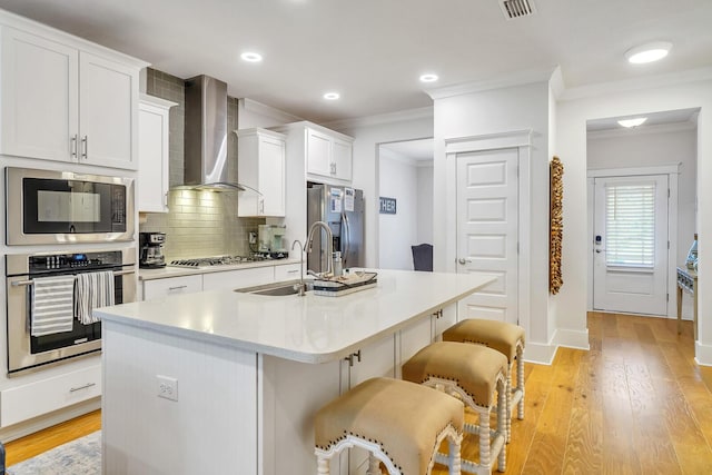 386 Grande Pointe Cir, Inlet Beach, FL 32461 - kitchen featuring appliances with stainless steel finishes, wall chimney exhaust hood, white cabinetry, light countertops, and a breakfast bar area