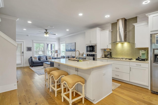 386 Grande Pointe Cir, Inlet Beach, FL 32461 - kitchen featuring wall chimney exhaust hood, stainless steel appliances, a kitchen island with sink, a breakfast bar, and white cabinetry