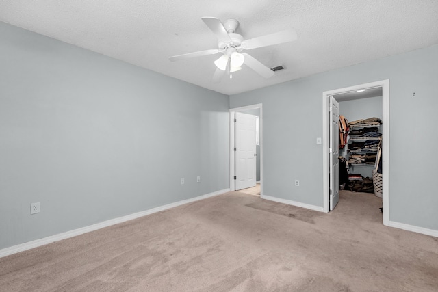 118 Cabana Way, Crestview, FL 32536 - unfurnished bedroom with a walk in closet, carpet floors, a closet, ceiling fan, and a textured ceiling