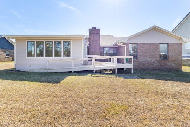 702 Beachcomber Dr, Lynn Haven, FL 32444 - back of property with a deck, a chimney, a lawn, and brick siding
