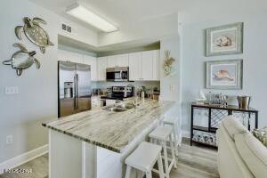 17757 Front Beach Rd Unit 507, Panama City Beach, FL 32413 - kitchen featuring stainless steel appliances, a peninsula, a kitchen bar, white cabinets, and light wood-style floors