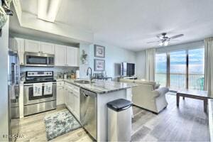 17757 Front Beach Rd Unit 507, Panama City Beach, FL 32413 - kitchen featuring appliances with stainless steel finishes, white cabinetry, a peninsula, ceiling fan, and light wood-type flooring