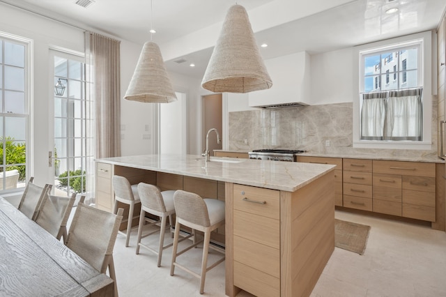 40 Silver Sea Ct Unit Aa4, Inlet Beach, FL 32461 - kitchen featuring light brown cabinetry, an island with sink, a breakfast bar area, light stone countertops, and tasteful backsplash