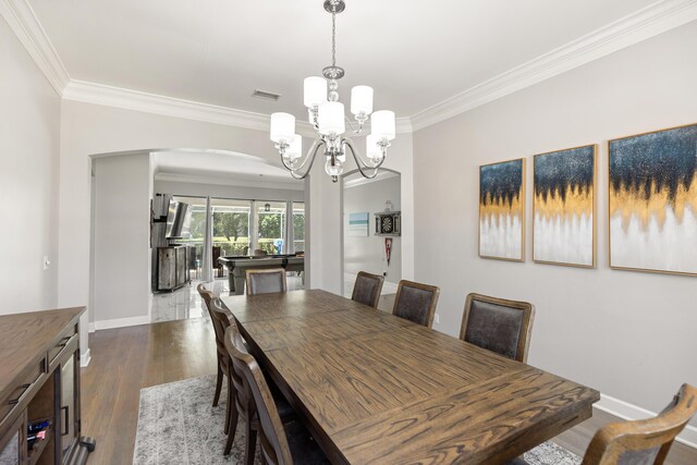 96 Garnet Pl, Destin, FL 32541 - dining room with crown molding, arched walkways, a chandelier, and dark wood-style floors