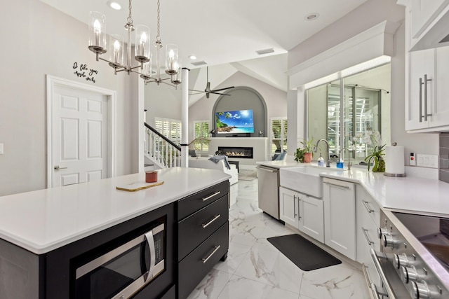 96 Garnet Pl, Destin, FL 32541 - kitchen featuring a glass covered fireplace, stainless steel appliances, light countertops, ceiling fan, and light marble finish flooring