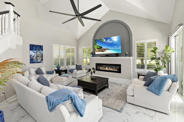 96 Garnet Pl, Destin, FL 32541 - living area with marble look tile flooring, high vaulted ceiling, plenty of natural light, a ceiling fan, and a glass covered fireplace