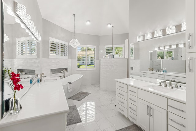 96 Garnet Pl, Destin, FL 32541 - bathroom with marble look tile flooring, two vanities, a soaking tub, a wainscoted wall, and tile walls