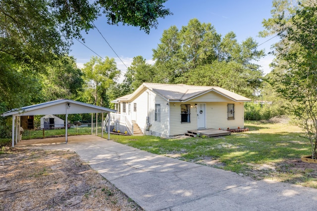 965 B St, Crestview, FL 32536 - view of front facade featuring a detached carport, concrete driveway, a front yard, and view of scattered trees