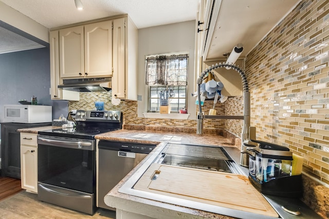 965 B St, Crestview, FL 32536 - kitchen featuring appliances with stainless steel finishes, under cabinet range hood, decorative backsplash, light wood-style flooring, and white cabinets