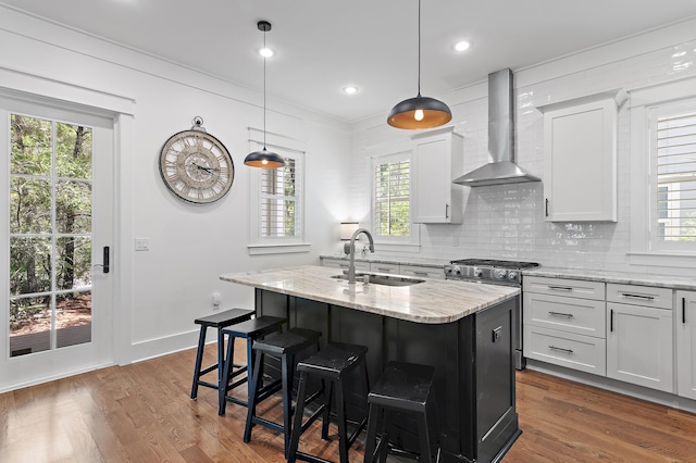 257 Matts Way, Santa Rosa Beach, FL 32459 - kitchen with wall chimney range hood, stainless steel gas range, an island with sink, light stone countertops, and dark wood-style flooring