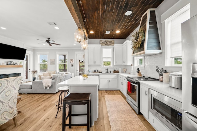 71 Childers Ln, Freeport, FL 32439 - kitchen featuring appliances with stainless steel finishes, wall chimney range hood, a breakfast bar area, recessed lighting, and light countertops