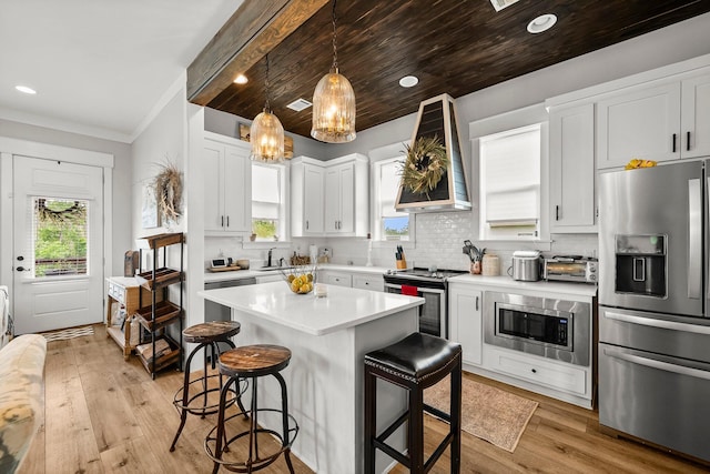 71 Childers Ln, Freeport, FL 32439 - kitchen featuring stainless steel appliances, wall chimney exhaust hood, a kitchen breakfast bar, light countertops, and white cabinets