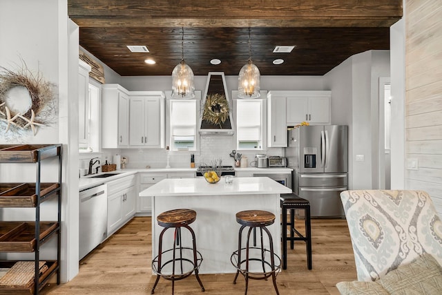 71 Childers Ln, Freeport, FL 32439 - kitchen with appliances with stainless steel finishes, premium range hood, a kitchen breakfast bar, light countertops, and light wood-style flooring